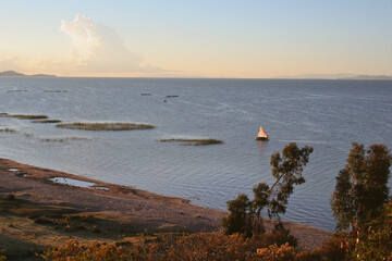 Red Morning light on a fishing boat with sail on Lake Titicaca, Peru in South America (Village Llachon)