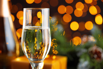Champagne glass on blurred garland lights background