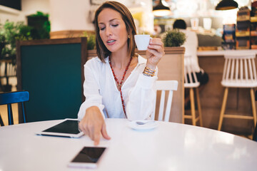 Fototapeta premium Focused adult lady drinking coffee in cafe