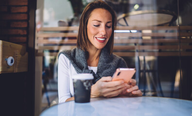 Smiling woman using smartphone in outdoor cafe