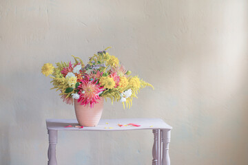 yellow and red flowers in vase on vintage shelf