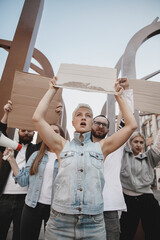 For better future. Group of activists giving slogans in a rally. Caucasian men and women marching together in a protest in the city. Look angry, hopeful, confident. Blank banners for your design or ad