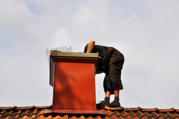 Unrecognizable modern chimney sweep checking out the chimney from the inside to see if it needs...