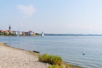 rocky beach on Lake Constance with Friedrichshafen and geyser in the background