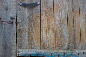Part of an old wooden door with a cloth handle nailed down with rusty nails. With a wooden plank at the bottom.