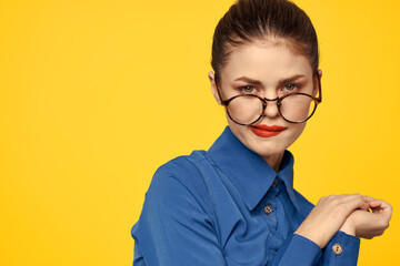 A woman in a blue shirt and glasses with bright makeup on her face is gesturing with her hands Copy Space