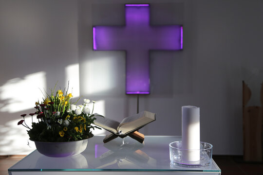 Altar in einer Kapelle mit einer Bibel und einem beleuchten Kreuz