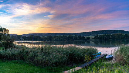 colorful sunset over lake landscape with small rowboats