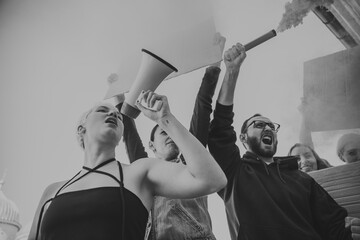 Black and white. Group of activists giving slogans in a rally. Caucasian men and women marching...