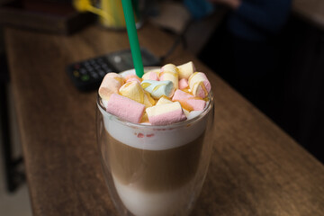 Delicious freshly made coffee latte with marshmallows stands on the table