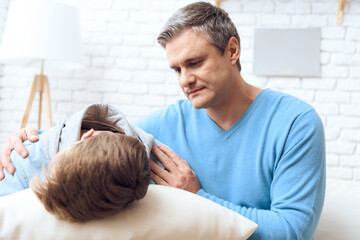 Dad reassures son who offended and lies on pillow.