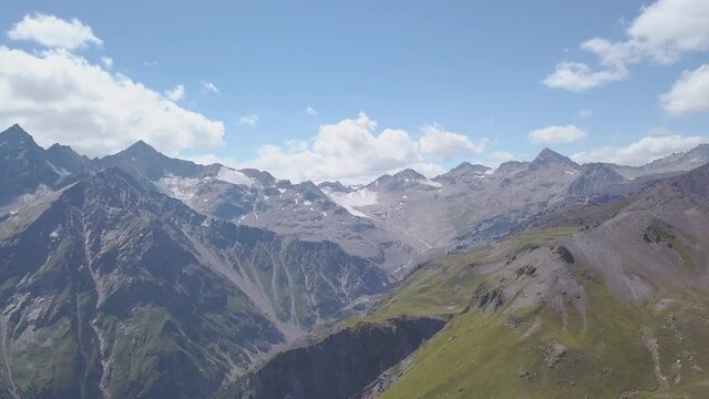 Top view of rocky mountains with patches of snow. Clip. Beautiful panorama of mountains with rocky peaks and snow in summer. Majestic mountains that take your breath away in clear weather