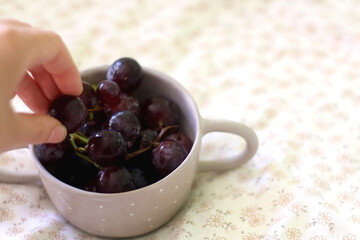 Unrecognizable person eating grapes from a bowl. Selective focus. 