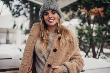Cheerful woman in warm outfit smiling at camera in snowy day
