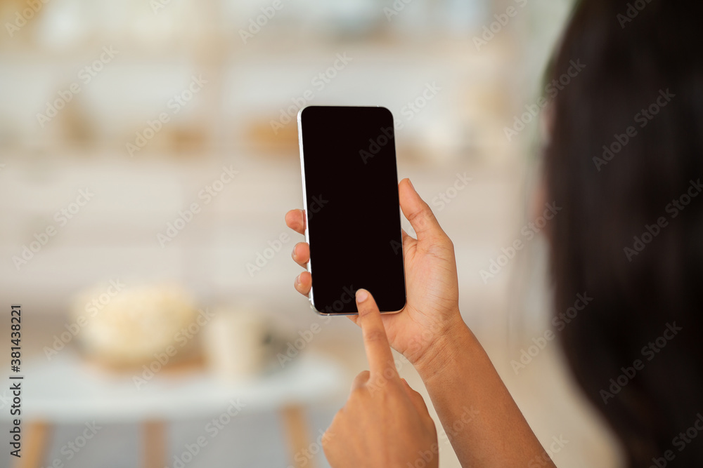 Wall mural african american woman touching mobile phone screen with mockup for mobile app or website design, in