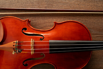 A close up of a violin with a bow on a wooden background
