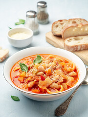 Italian minestrone soup with parmesan cheese and basil on blue concrete background