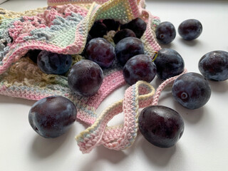 Fresh plum in a multicolored string bag on a white background. Photo from above. Zero waste. Ecology. Care for the environment. Proper nutrition, vegetarianism