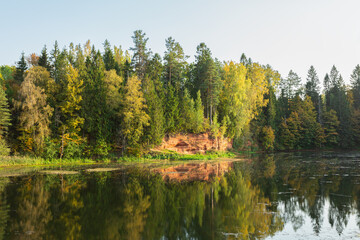 Fototapeta na wymiar Picturesque lake and a sand quarry in the autumn forest in Rozhdestveno, Saint Petersburg, Russia. Horizontal image.