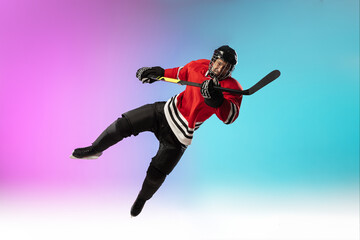 In flight. Male hockey player with the stick on ice court and neon gradient background. Sportsman wearing equipment, helmet practicing. Concept of sport, healthy lifestyle, motion, wellness, action.