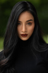 Asian woman in black shirt glaring into the camera. She looks serious, concerned or worried. Close...