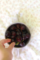 Unrecognizable person eating grapes from a bowl. Top view.