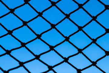 Naklejka premium Old rope mesh against the blue sky. Close-up with blurred background.