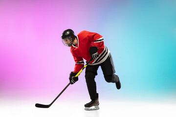 Goal. Male hockey player with the stick on ice court and neon gradient background. Sportsman wearing equipment, helmet practicing. Concept of sport, healthy lifestyle, motion, wellness, action.