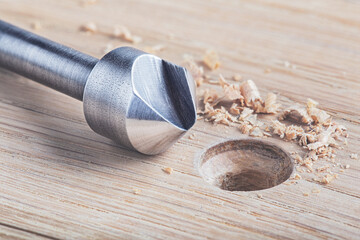 Countersink drill bit make sink in hole for screw in wooden plank.