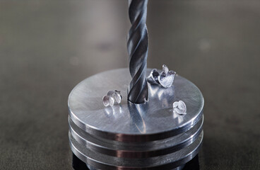 metal drill bit make holes in steel billet on industrial drilling machine. Metal work industry....
