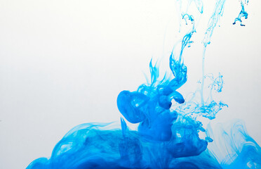 Closeup of a blue ink in water in motion isolated on white. Ink swirling underwater. Colored abstract smoke explosion effect. Abstract background with copy space..