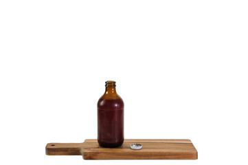 Obraz na płótnie Canvas Little brown glass bottle on wooden cutting board with metallic cap beside on white background