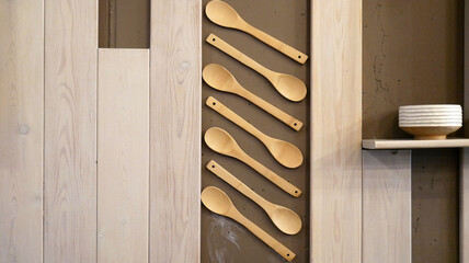 Wooden spoons hang on the wall as an interior item for a cafe or restaurant. The concept of food and ecology.