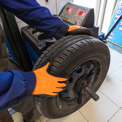 Mechanic working with wheel balancing machine at tire service, closeup