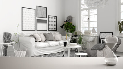 White table or shelf with crystal hourglass measuring the passing time over scandinavian black and white living room, sofa, carpet, architecture interior design, copy space background