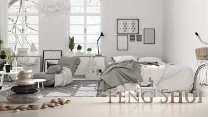 White table shelf with pebble balance and 3d letters making the word feng shui over white and black scandinavian bedroom with double bed, armchair, carpet, zen concept interior design