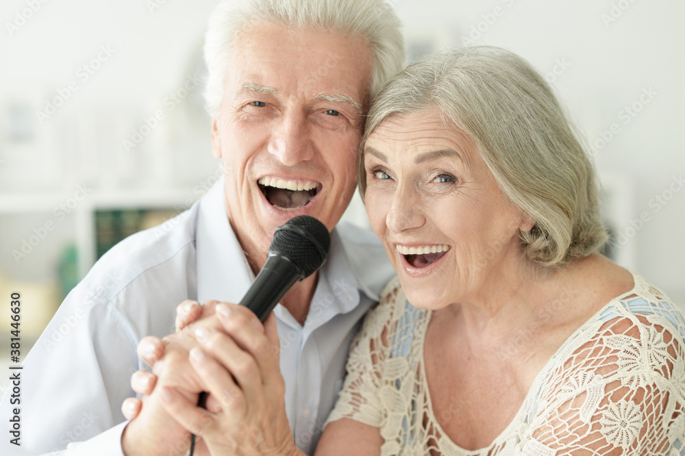 Wall mural Close up portrait of senior couple singing karaoke