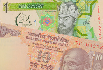 A macro image of a orange ten rupee bill from India paired up with a green and yellow one manat...