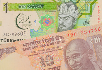 A macro image of a orange ten rupee bill from India paired up with a green and yellow one manat...