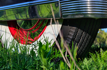Close up detail of classic, vintage, luxury car's rear wheel parked in grass with whitewall tires,...