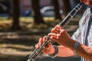 Fototapeta premium Close up young man playing clarinet on walking street. Street musician. Music, art, creativity concept.