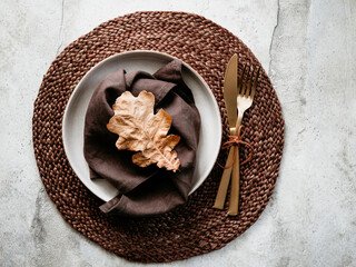 Top view of decorated table setting dish with fallen leaf. Thanksgiving or Autumn festive dinner concept.