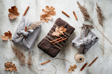 Top view of wrapped gifts by linen fabric in furoshiki eco style with Autumn decor. Thanksgiving or Halloween celebration concept.