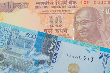 A macro image of a orange ten rupee bill from India paired up with a blue, plastic five hunded tenge bank note from Kazakstan.  Shot close up in macro.