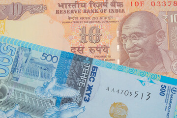 Fototapeta premium A macro image of a orange ten rupee bill from India paired up with a blue, plastic five hunded tenge bank note from Kazakstan. Shot close up in macro.