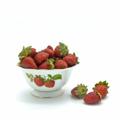A porcelain bowl with fresh strawberries. Juicy ripe berries with green leaves. The same pattern on the vase. Isolated over white background.