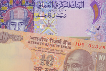 A macro image of a orange ten rupee bill from India paired up with a colorful one rial note note from Oman.  Shot close up in macro.