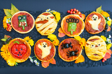 Halloween mini pizza with cheese, olives and ketchup. Decorated mummy, ghost, spiders, zombie, pumpkin. Funny crazy food for kids.