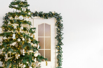 Congratulatory new year card. Christmas tree decorated with a garland, on the background of the door. Place for text.