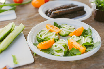 Fresh vegetable salad, on the table on the background of grilled sausages.